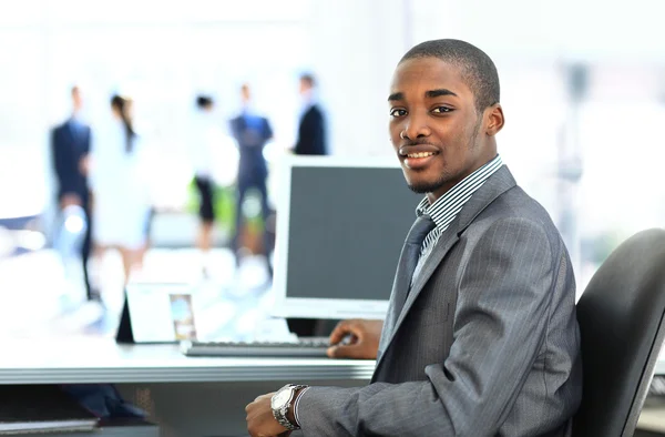 Retrato del hombre de negocios afroamericano sonriente con ejecutivos trabajando en segundo plano —  Fotos de Stock