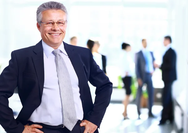 Succesvolle business man die met zijn personeel in de achtergrond op kantoor — Stockfoto