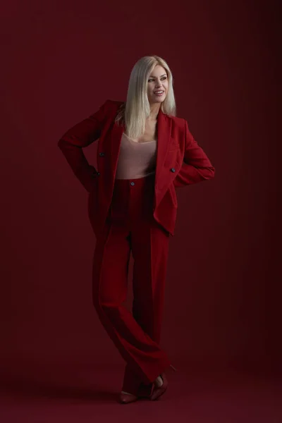 Mode junge Frau im roten Anzug. Roter Hintergrund. — Stockfoto
