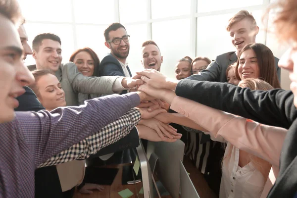 På nära håll. unga anställda med en gest att visa sin enhet — Stockfoto