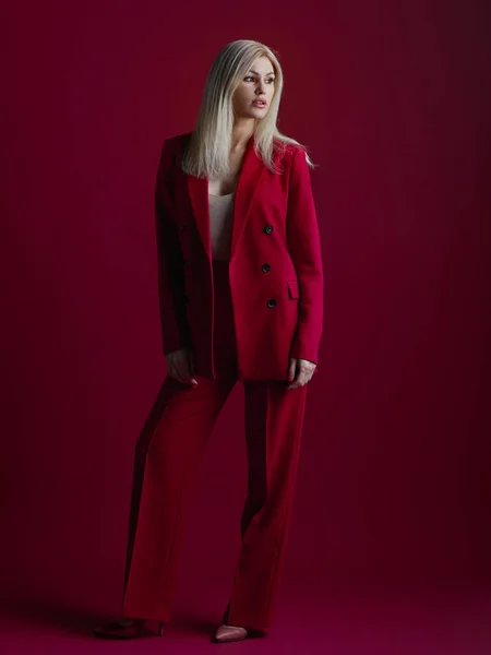 Mode junge Frau im roten Anzug. Roter Hintergrund. — Stockfoto