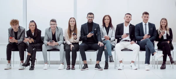 Группа молодых бизнесменов, которые смотрят на экраны своих смартфонов. — стоковое фото