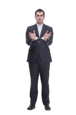 A man in a black business suit holding hands in handcuffs in front of his chest