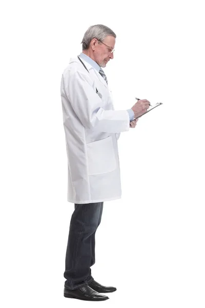 Front view of mature thoughtful doctor writing on clipboard — Stok fotoğraf