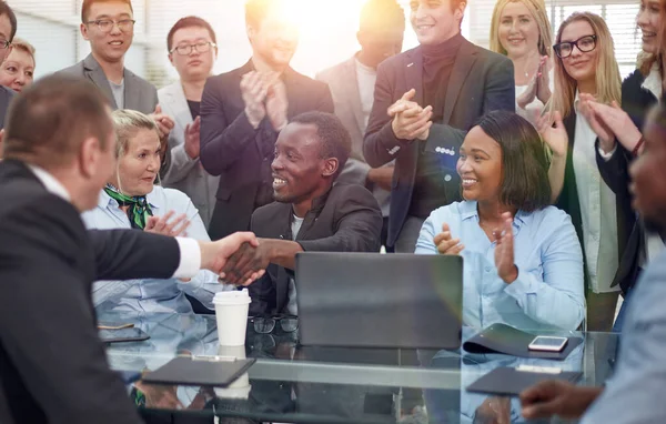 Zakenmensen schudden handen over een bureau. — Stockfoto