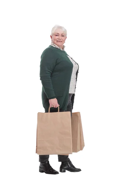 Ευτυχισμένη ηλικιωμένη γυναίκα απλώνει τα χέρια της με τσάντες για ψώνια και χαμογελά ενώ στέκεται απομονωμένη σε λευκό φόντο. — Φωτογραφία Αρχείου