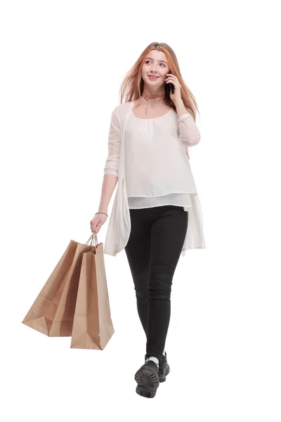 Retrato de una chica bastante feliz hablando en el teléfono móvil mientras sostiene bolsas de compras y mirando hacia otro lado —  Fotos de Stock