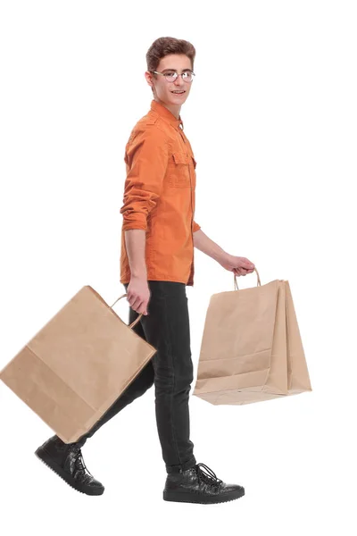 Boční pohled na jít mladý muž v jasné košili s nákupními taškami. — Stock fotografie