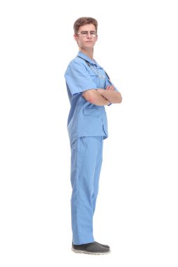 Mavi üniformalı, ayakta bekleyen genç bir erkek doktorun tam boy profil çekimi.