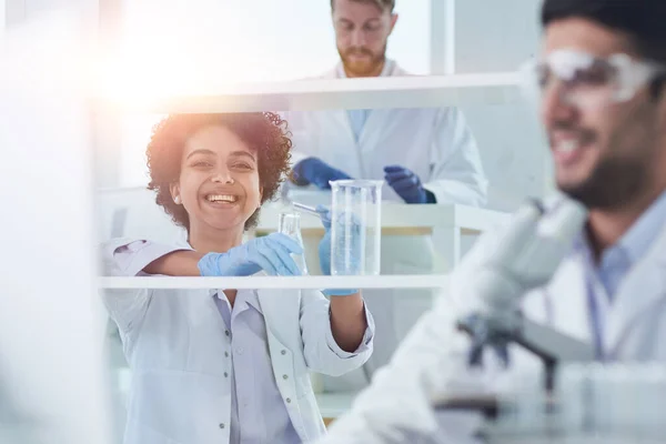 Des scientifiques souriants regardant des bras de caméra croisés en laboratoire — Photo