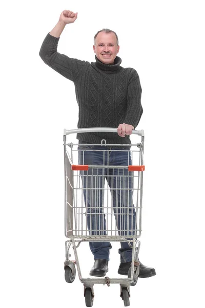 Ganzkörperporträt eines Mannes, der neben einem leeren Einkaufswagen mit erhobener Hand posiert — Stockfoto