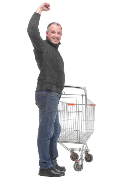 Kazak ve kot giyen bir adam boş bir alışveriş arabasını itiyor. — Stok fotoğraf