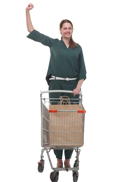 Una mujer sonriente posando junto a un carrito de compras vacío aislado sobre fondo blanco —  Fotos de Stock