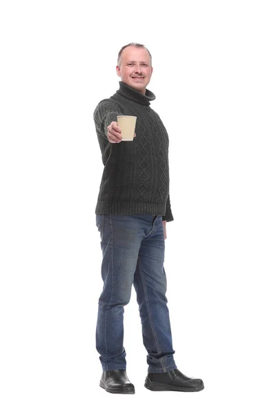 Pleasant man in jeans offering a cup of coffee and smiling at the camera Stock Image