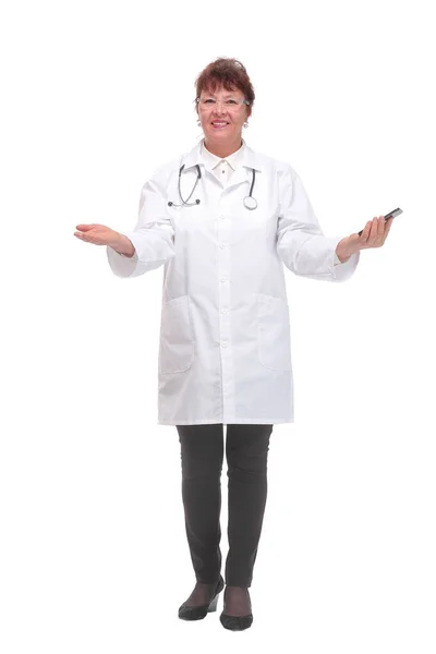 스마트폰을 사용하면서 고립된 하얀 배경에 서 있는 중년 여성 의사의 초상화 사진. — 스톡 사진