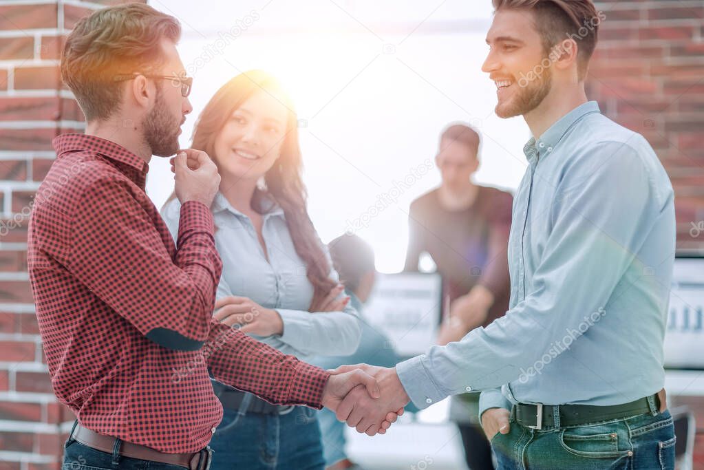 Smiling businessman shaking hands with colleague in office.