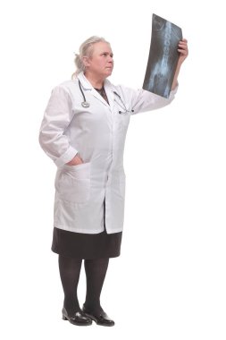 Doktor röntgen görüntülerini analiz ediyor. Kameraya bakıyor ve gülümsüyor.