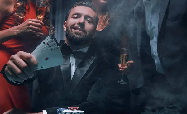 A happy company celebrates a victory in poker with champagne. — Stock Photo, Image