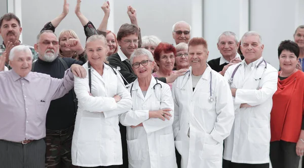 Glückliche Ärzte stehen mit Team im Krankenhaus mit verschränkten Armen auf dem Flur und schauen in die Kamera — Stockfoto