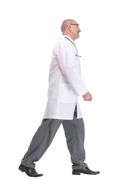 Mature doctor with stethoscope walking on white background — Stock Photo, Image