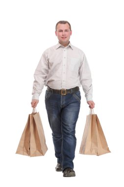 Kot pantolon giyen genç bir işadamı alışveriş torbalarıyla yürüyor.