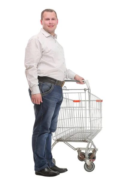 Happy young man with empty shopping cart isolated on white background — Stock Photo, Image