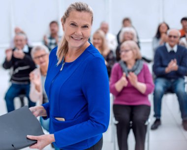Orta yaşlı yönetici kadın kameraya bakıyor.
