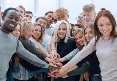 Çeşitli gençler ellerini birleştiriyor.