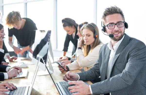 Uśmiechnięty menedżer call center siedzi przy biurku Zdjęcia Stockowe bez tantiem