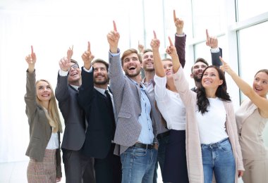 Bir grup mutlu genç iş adamı yukarıyı gösteriyor.