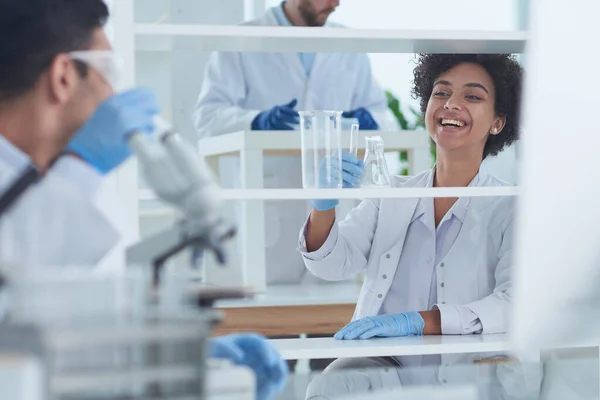 Des scientifiques souriants regardant des bras de caméra croisés en laboratoire — Photo