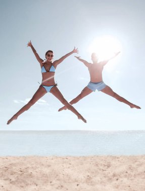 Kumsalda zıplayan mutlu bir çiftin fotoğrafı..