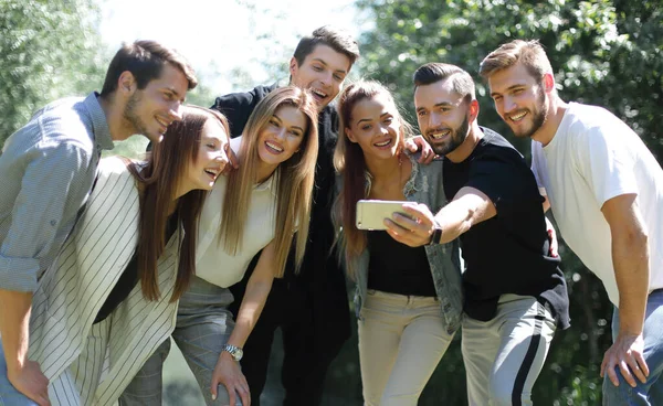 Grupo de amigos se toma una selfie en el fondo del parque de la ciudad — Foto de Stock