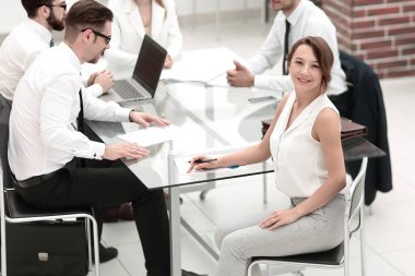 Gülümseyen bir çalışan ve iş adamı masamızda oturuyor. Takım çalışması kavramı.