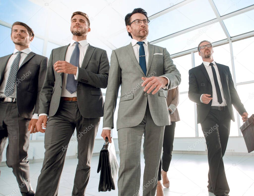 Confident business partners walking down in office building and talking