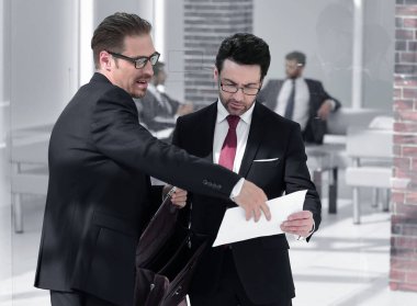 İki odaklı arkadaşları modern bir ofiste durmak ve derinden belgeleri tartışmak