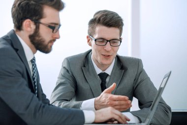 Kapat. Bir dizüstü bilgisayardaki bilgiyi analiz eden iki iş adamı. Işık arkaplanında izole