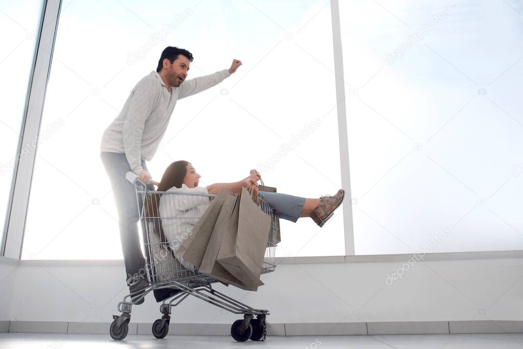 married young couple riding in shopping cart. photo with copy space