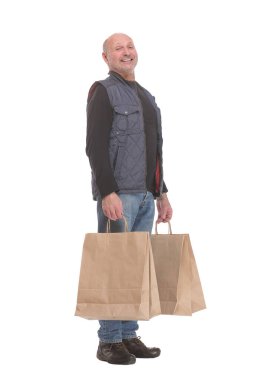 Zarif, modern, olgun bir adam alışveriş torbalarını tutuyor ve kameraya gülümsüyor.