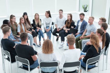 Çemberin içinde oturan bir grup benzer fikirli genç insan. iş ve eğitim