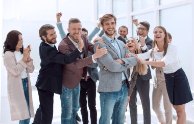 Neşeli iş ekibinin arka planında gülümseyen girişimci. başarı kavramı