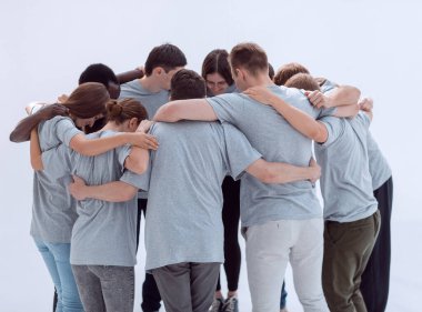 Bir grup genç insan bir çember oluşturup birbirlerine sarılıyorlar. beyaz üzerine izole