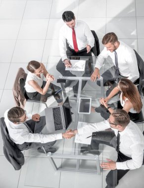 Büro çalışanları araştırma yapmak ve yeni fikirleri uygulamak için bir masa etrafında toplandılar..