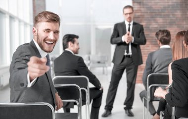 ofiste toplantı sırasında kameraya bakmak için dönüm kendine güvenen genç işadamı.