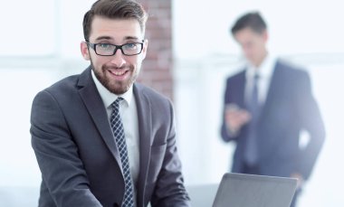 Ofiste dizüstü bilgisayar kullanırken gülümseyen yakışıklı iş adamının portresi