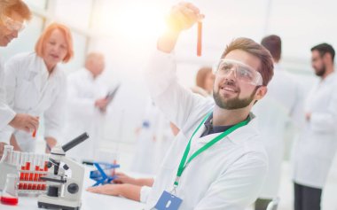 Test sonuçlarıyla birlikte test tüpüne bakan genç bir bilim adamı. Sağlık koruma kavramı.