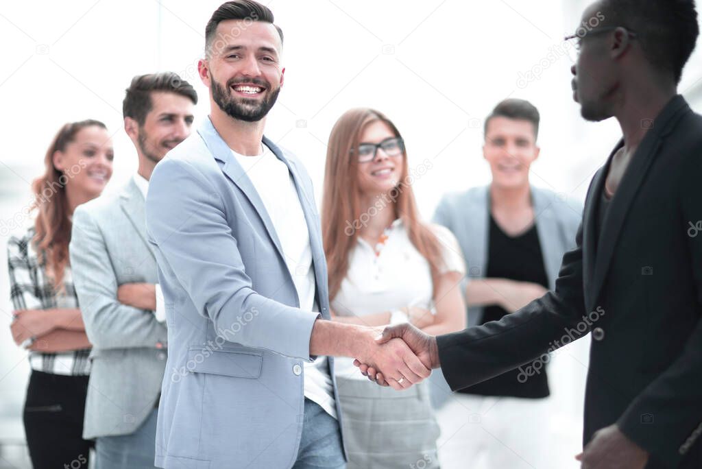 Two cheerful businessmen handshaking at formal meeting, starting finishing negotiations, african entrepreneur wearing black suit white shirt and caucasian partner shake hands, making profitable deal