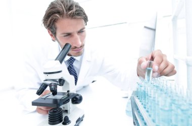 Araştırmacı test tüpleri ile mavi bir sıvıyı denetler