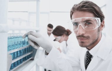 Beyaz paltolu bir genç bilim adamı araştırma klinik laboratuvarda gerçekleştirir.