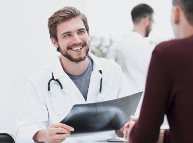 Doktorlar hasta ile masa başında oturan x-ray görüntü tartışmak.